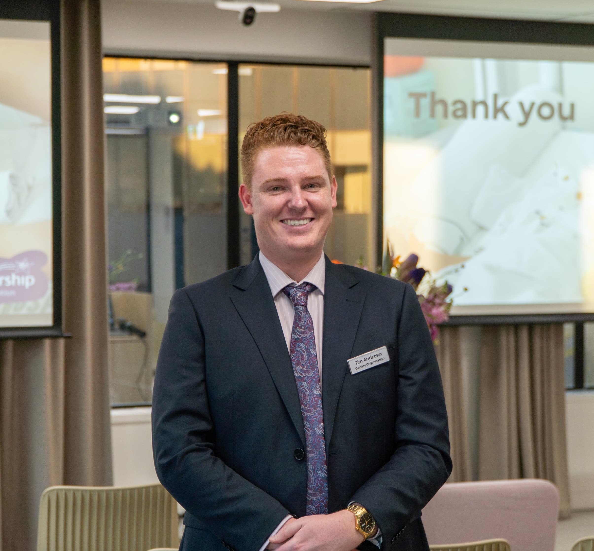 Tim Andrews, founder of Canary, smiling, in a suit and tie with a Canary name badge.